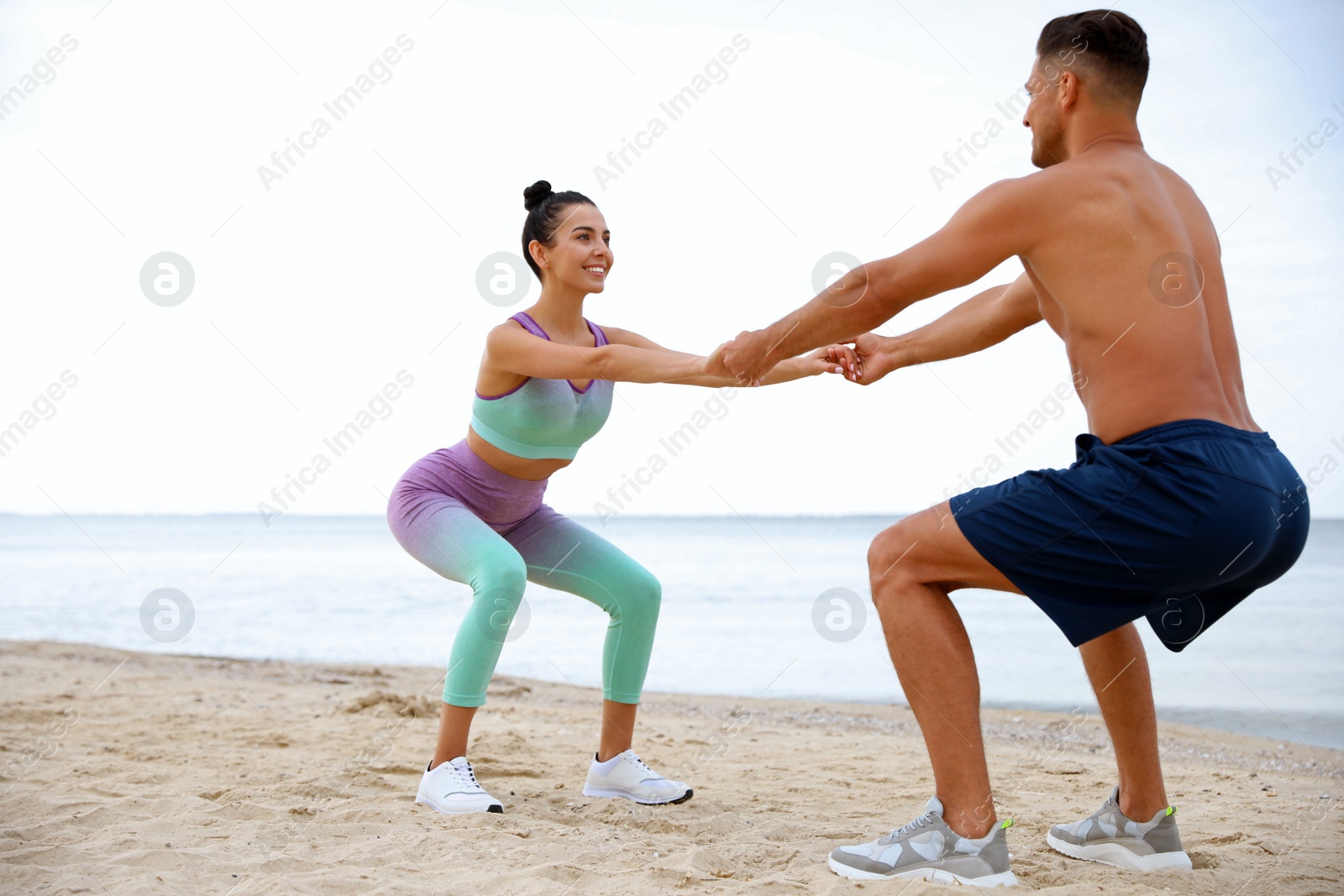 Photo of Couple doing exercise together on beach. Body training