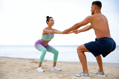 Couple doing exercise together on beach. Body training