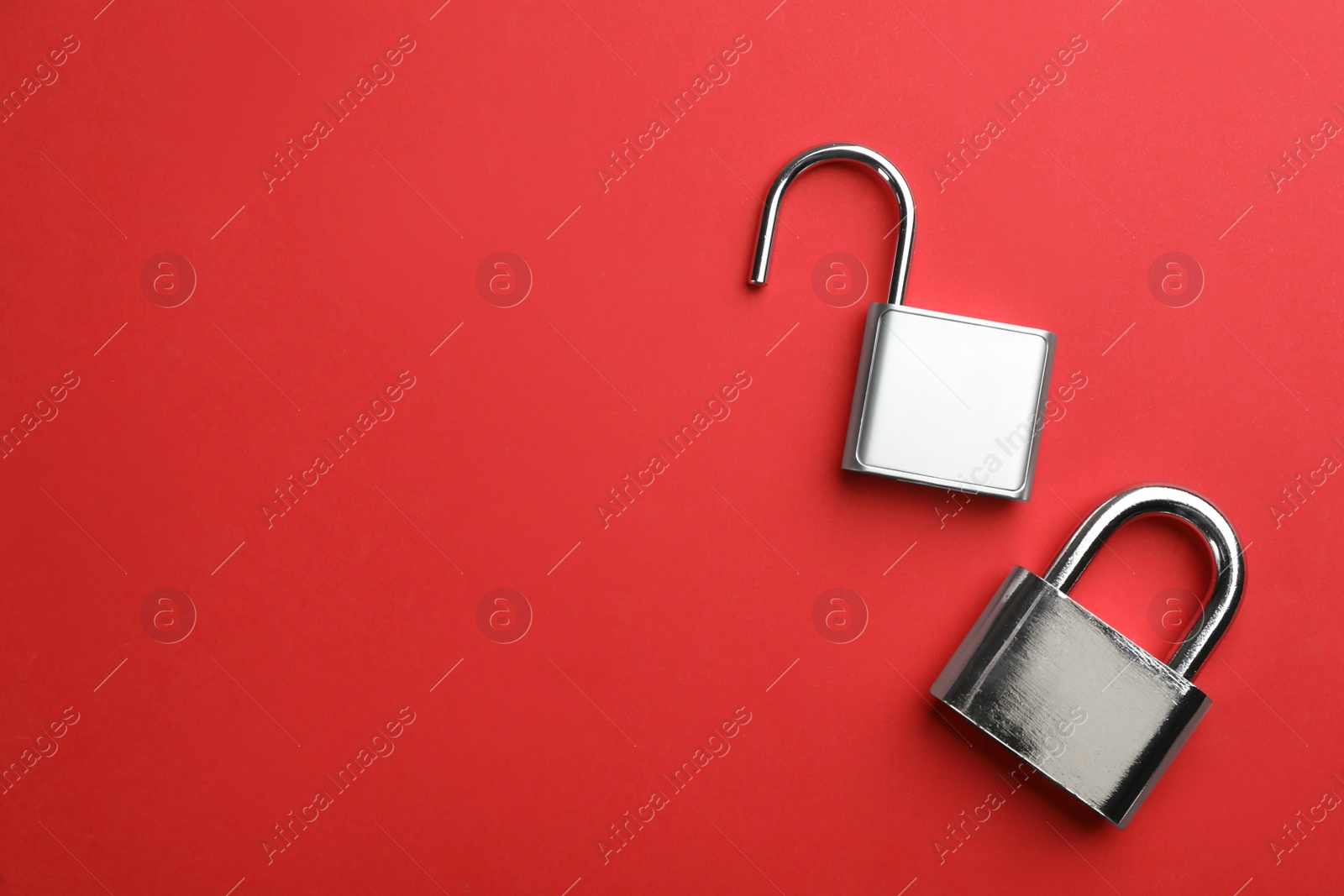Photo of Modern padlocks on red background, flat lay. Space for text