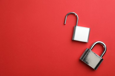 Modern padlocks on red background, flat lay. Space for text