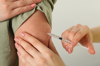 Photo of Diabetes. Woman getting insulin injection on grey background, closeup