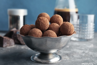 Photo of Bowl with tasty chocolate truffles on grey table