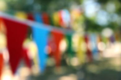 Photo of Blurred view of colorful bunting flags in park. Party decor