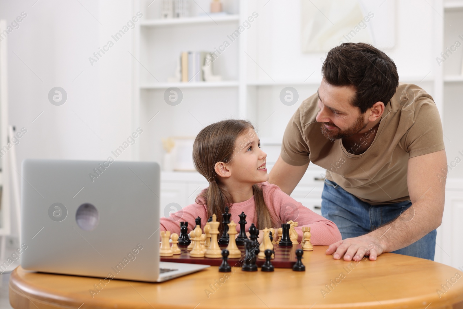 Photo of Father teaching his daughter to play chess following online lesson at home