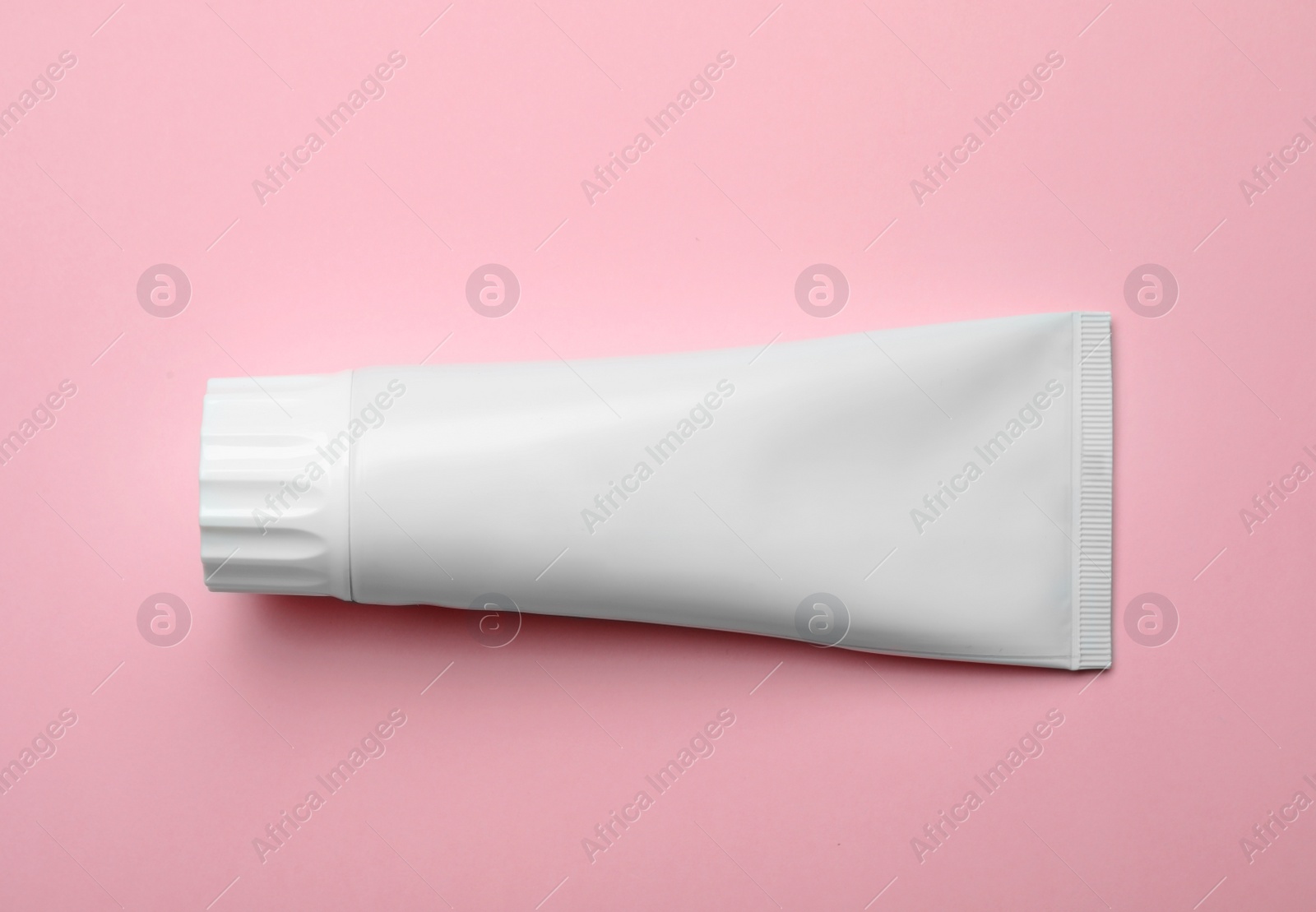 Photo of Blank tube of toothpaste on color background, top view