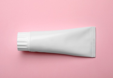 Photo of Blank tube of toothpaste on color background, top view