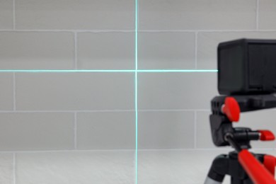 Photo of Cross lines of laser level on white brick wall