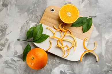 Orange fruits with peels on light grey table, flat lay