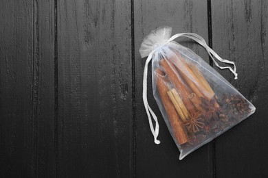 Photo of Scented sachet with cinnamon sticks and anise stars on wooden table, top view. Space for text