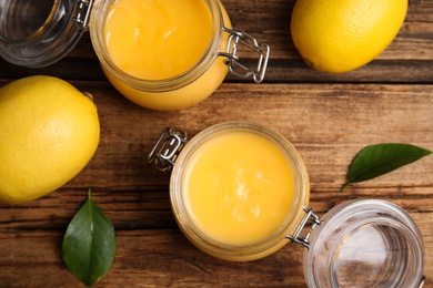 Delicious lemon curd and fresh fruits on wooden table, flat lay