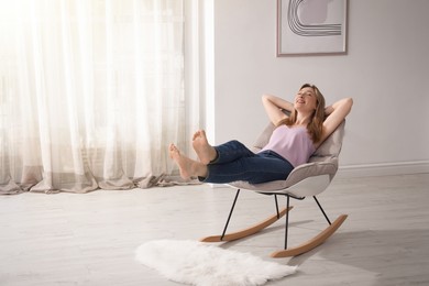 Photo of Beautiful young woman sitting in rocking chair at home