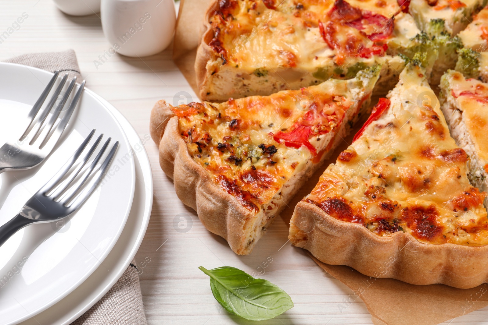 Photo of Tasty quiche with tomatoes and cheese served on white wooden table, closeup