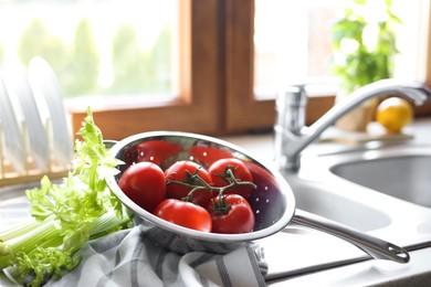 Photo of Fresh raw tomatoes and celery on countertop near sink in kitchen