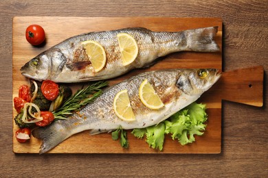 Photo of Delicious baked fish and vegetables on wooden table, top view