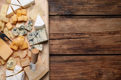 Photo of Cheese plate on wooden table, top view. Space for text