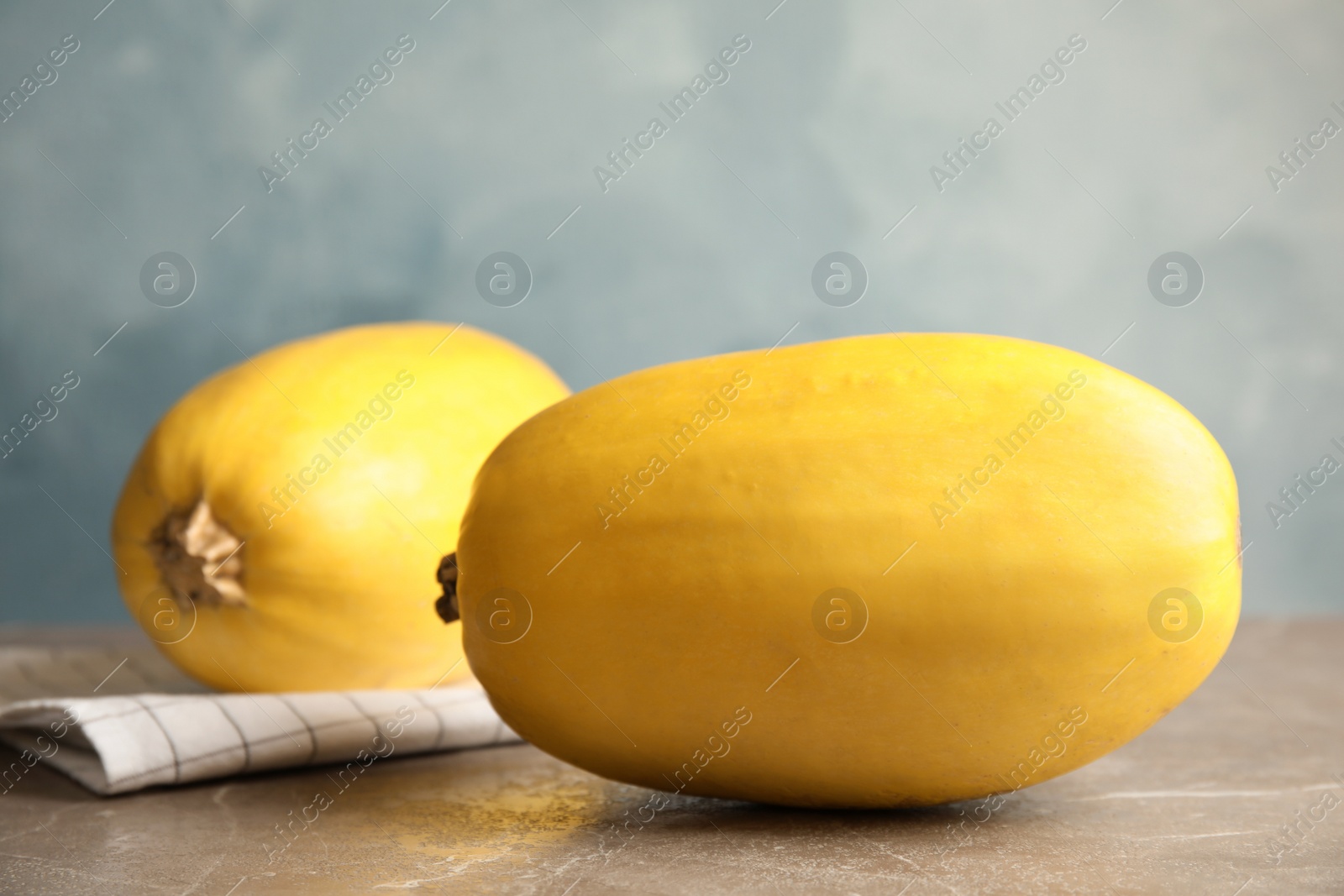 Photo of Ripe spaghetti squashes on gray table against color background
