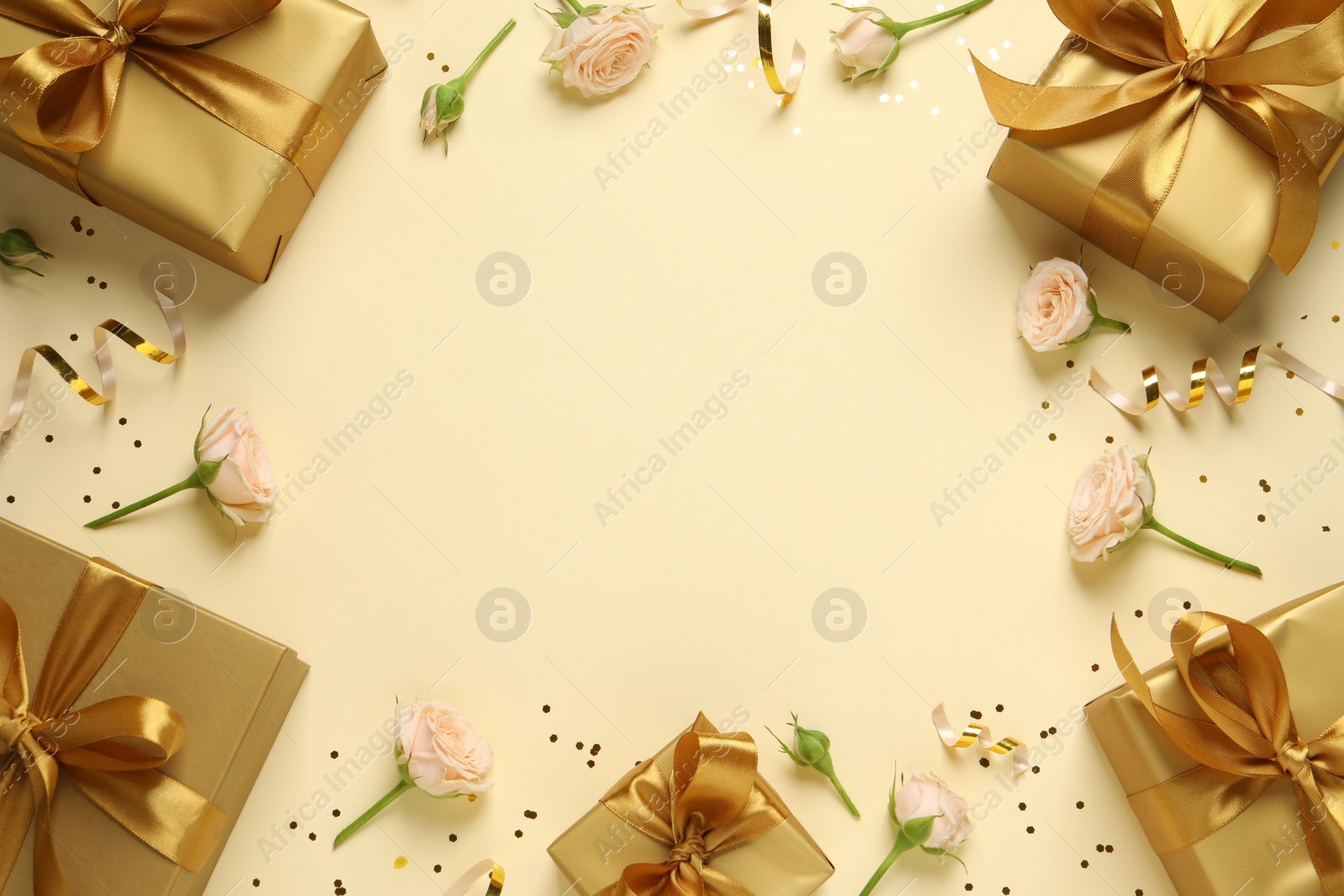 Photo of Frame of beautifully wrapped gift boxes, flowers and confetti on beige background, flat lay. Space for text