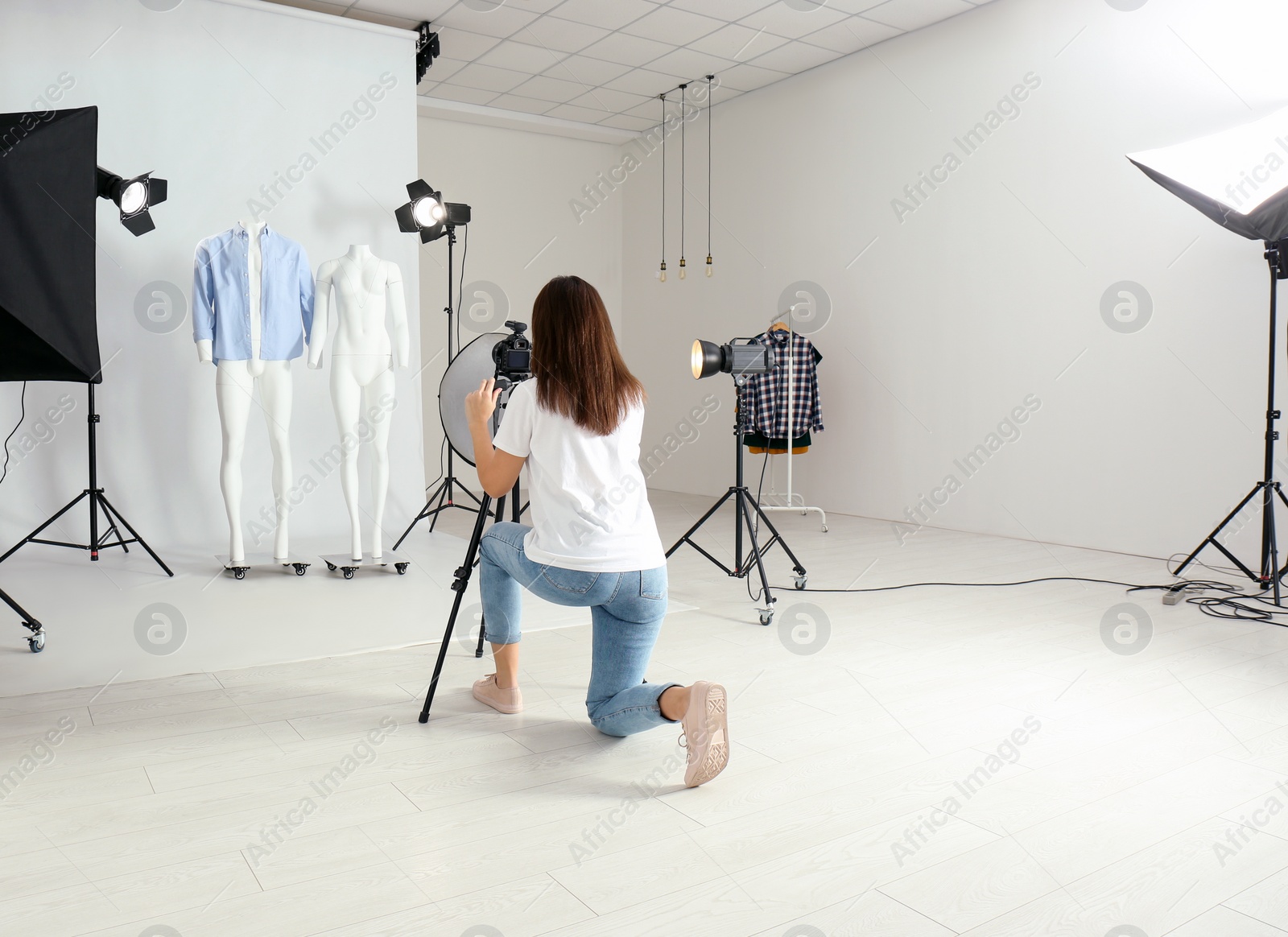 Photo of Professional photographer taking picture of ghost mannequins with modern clothes in photo studio