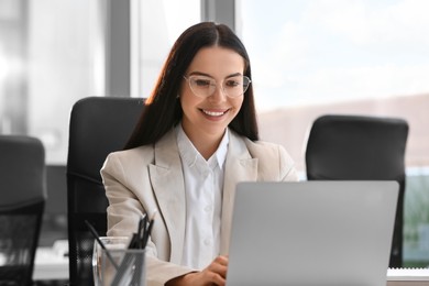Photo of Happy woman using modern laptop in office
