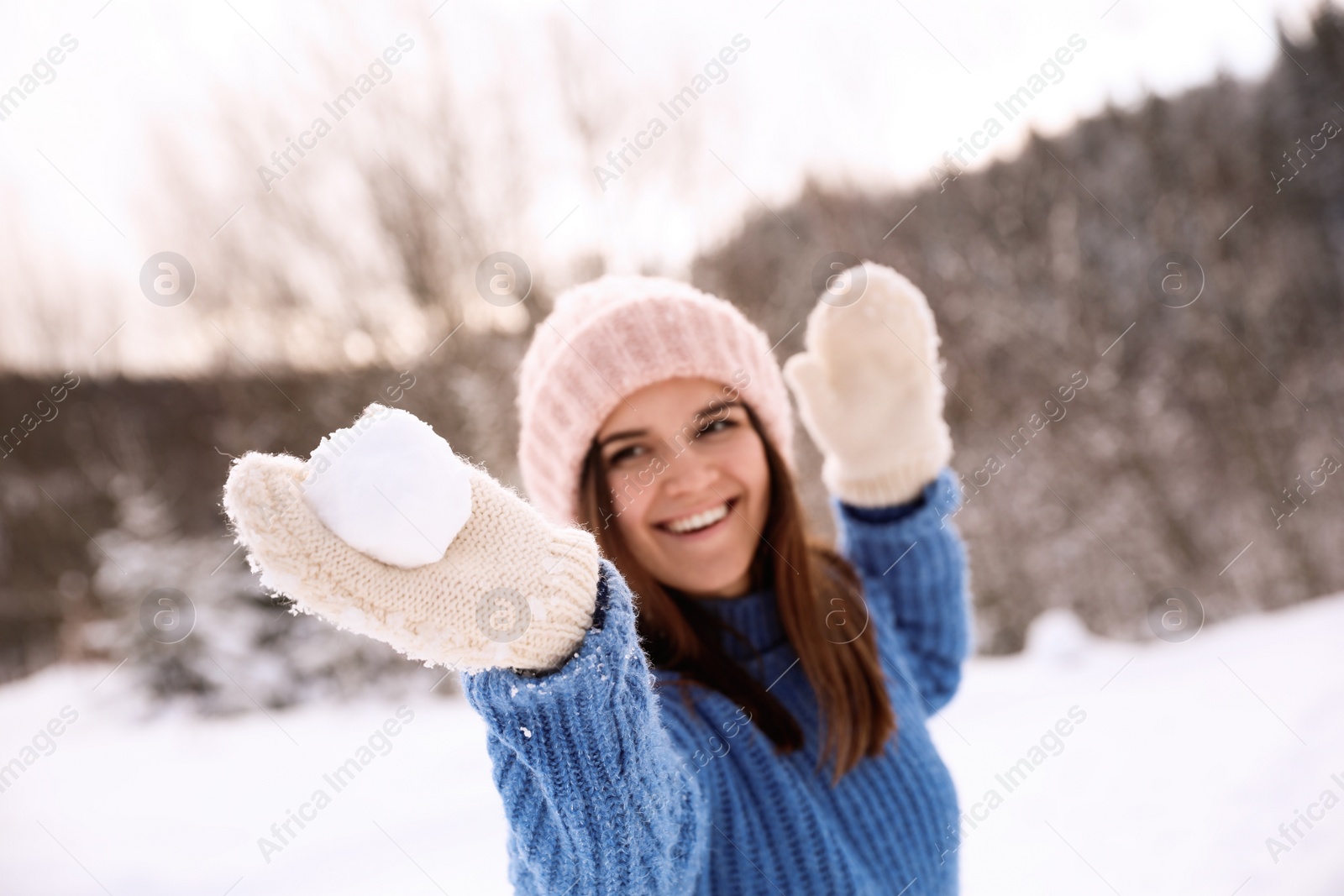 Photo of Young woman with snowball outdoors, focus on hand. Winter vacation