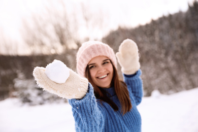 Photo of Young woman with snowball outdoors, focus on hand. Winter vacation