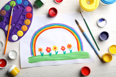 Photo of Flat lay composition with child's painting of flowers and rainbow on white wooden table