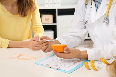 Nutritionist consulting patient at table in clinic, closeup
