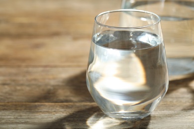 Photo of Glass of water on wooden table, closeup with space for text. Refreshing drink