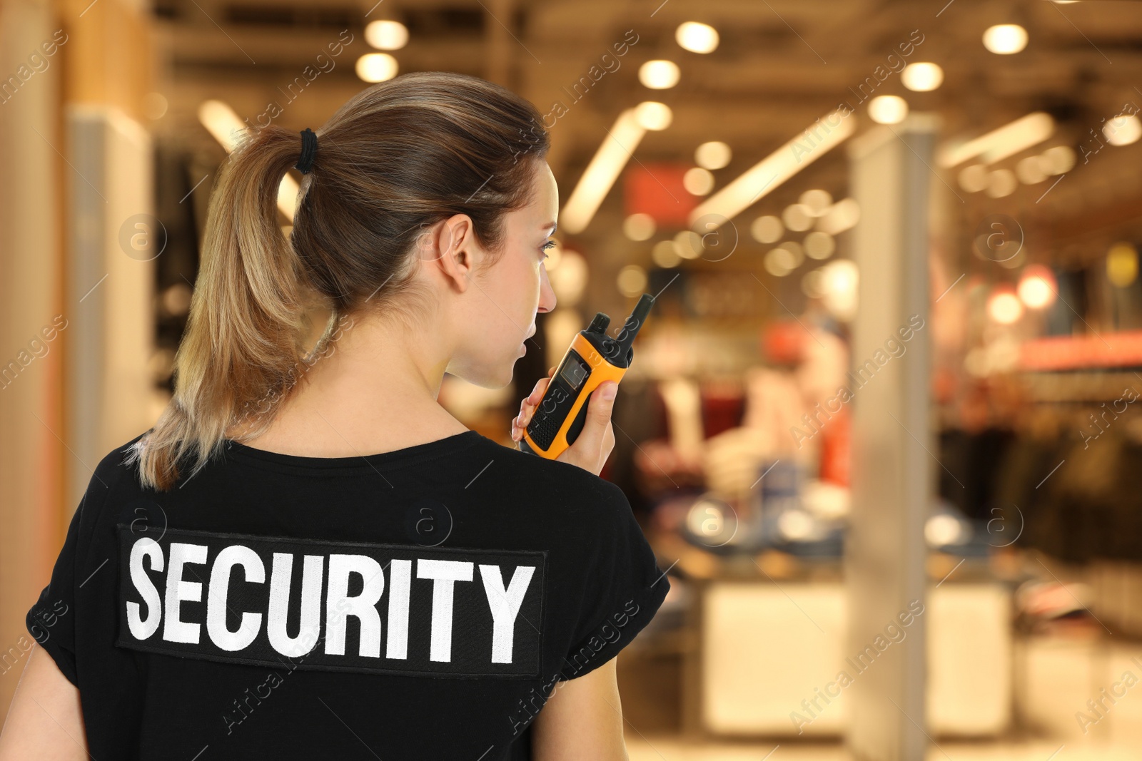 Image of Female security guard wearing uniform using portable radio transmitter in shopping mall