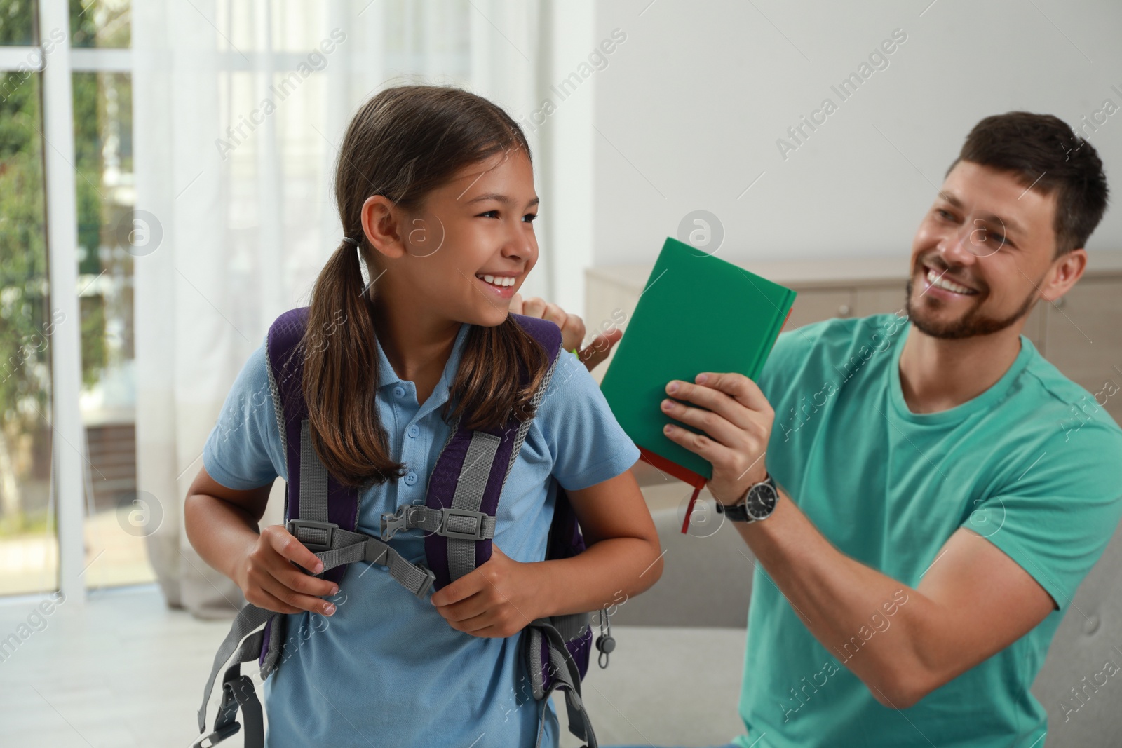 Photo of Father helping his daughter to get ready for school at home