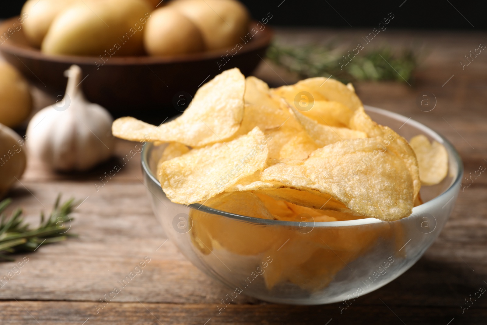 Photo of Bowl of crispy potato chips on wooden table. Space for text