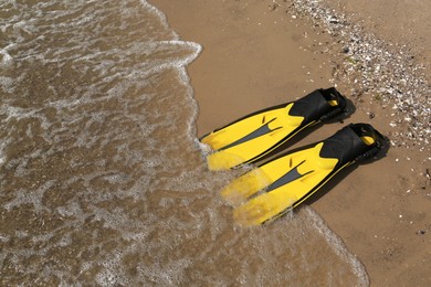 Photo of Pair of yellow flippers on sand near sea