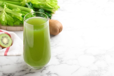 Photo of Glass with fresh celery juice on white marble table, closeup. Space for text