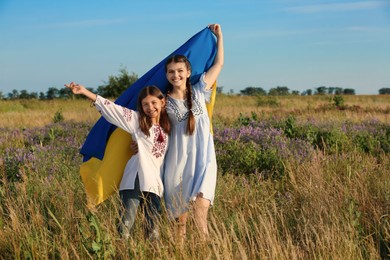 Happy girls with national flag of Ukraine in field