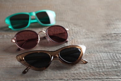 Many different stylish sunglasses on wooden background