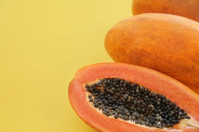 Photo of Fresh ripe cut and whole papaya fruits on light green background, flat lay. Space for text