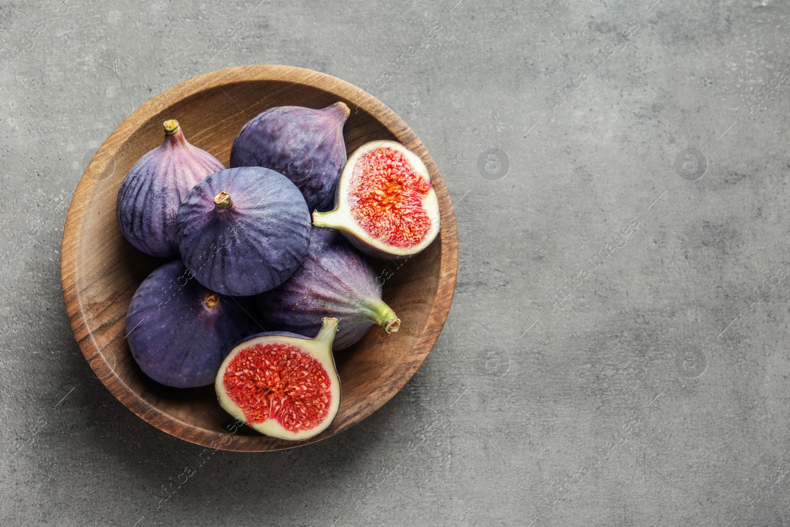 Photo of Bowl with fresh ripe figs on gray background, top view. Space for text