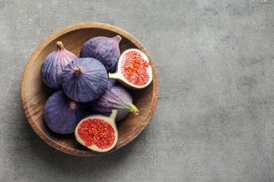 Bowl with fresh ripe figs on gray background, top view. Space for text