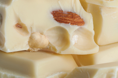 Photo of Pieces of white chocolate with nuts as background, closeup