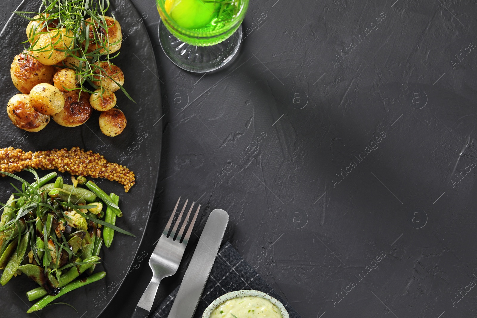Photo of Delicious salad with tarragon, mustard and grilled potatoes served on black textured table, flat lay. Space for text