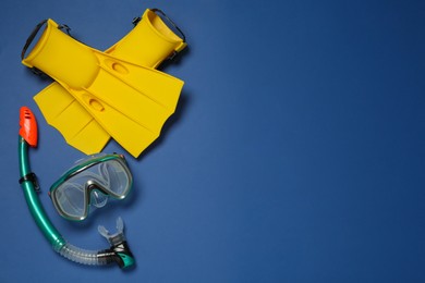 Photo of Pair of flippers, snorkel and diving mask on blue background, flat lay