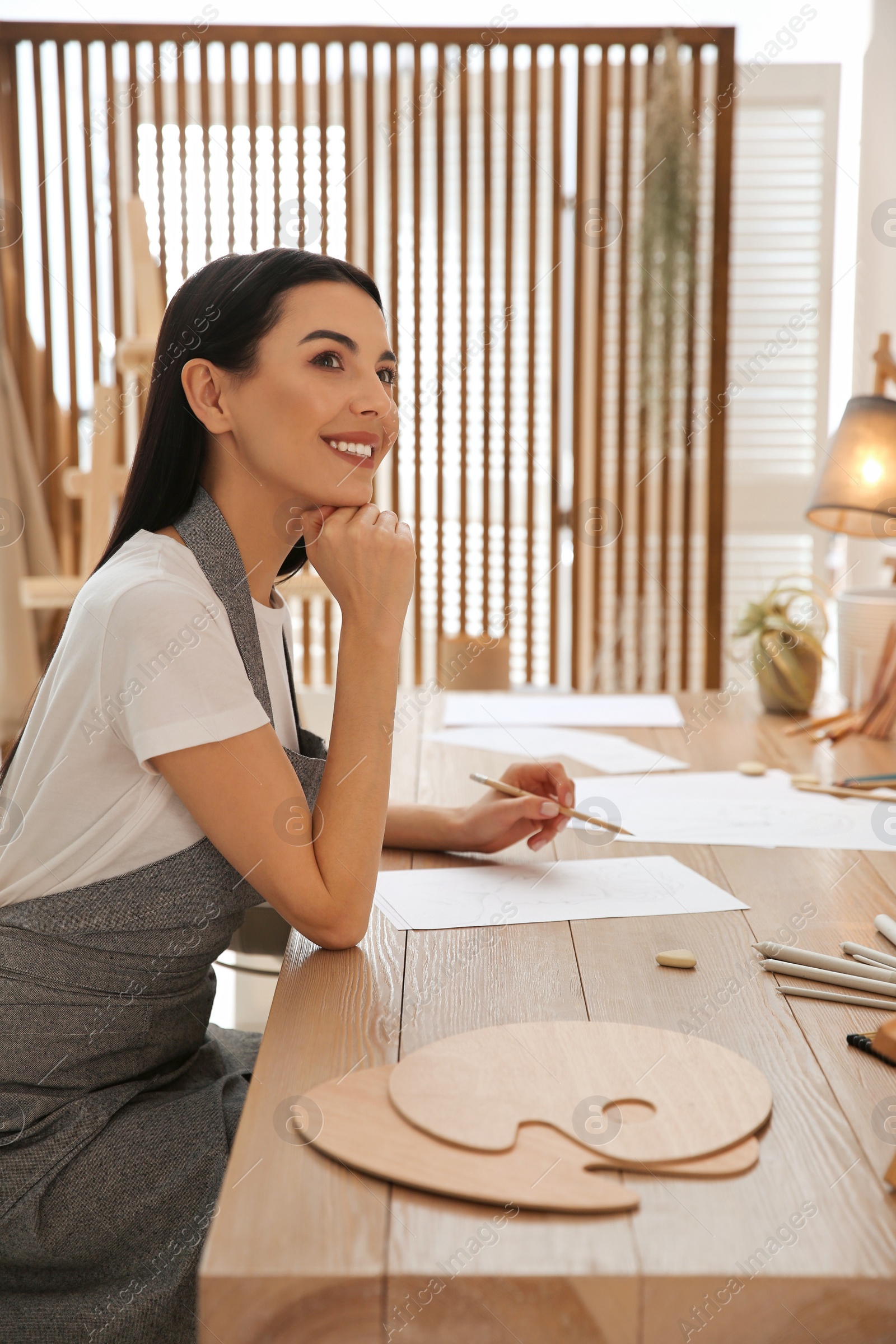 Photo of Young woman drawing with pencil at table indoors