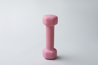 Photo of Pink rubber coated dumbbell on light background