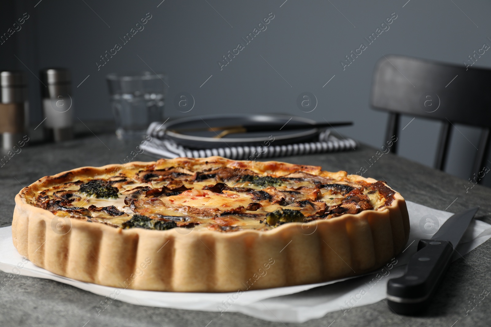 Photo of Delicious quiche with mushrooms and knife on dark grey table, closeup