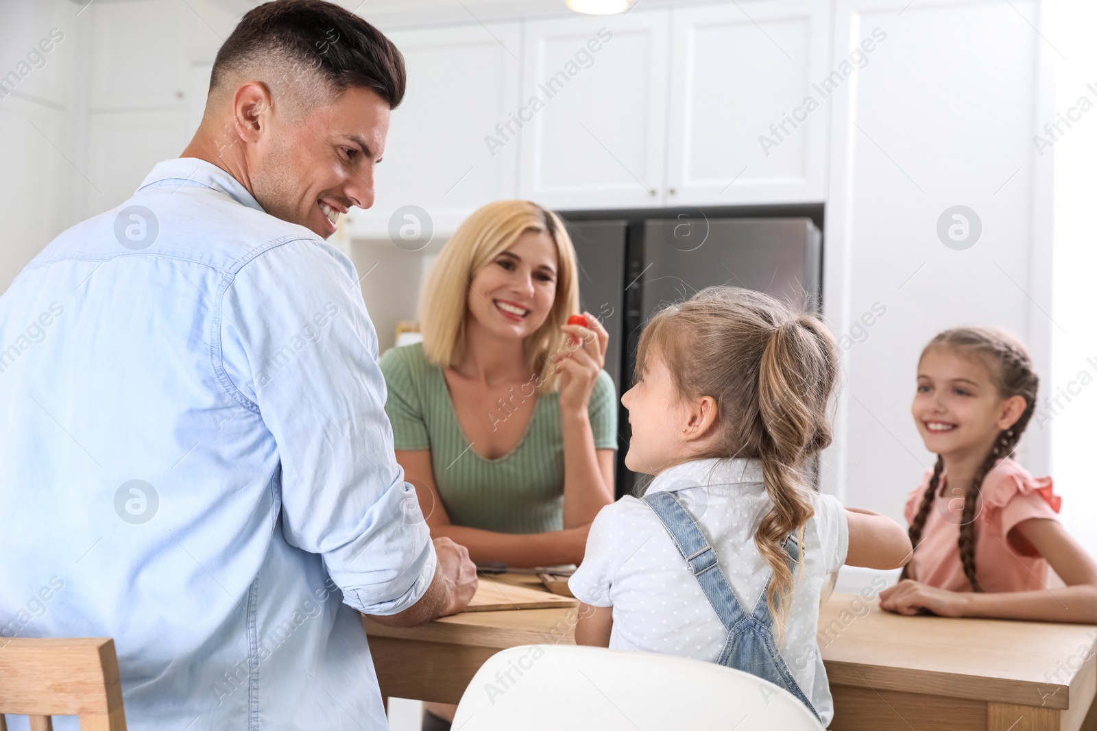 Photo of Happy family cooking together at table in modern kitchen