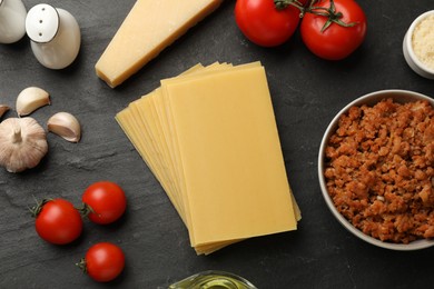 Photo of Flat lay composition with products for cooking lasagna on dark textured table