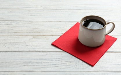 Cup of coffee, clean paper napkin and space for text on wooden background