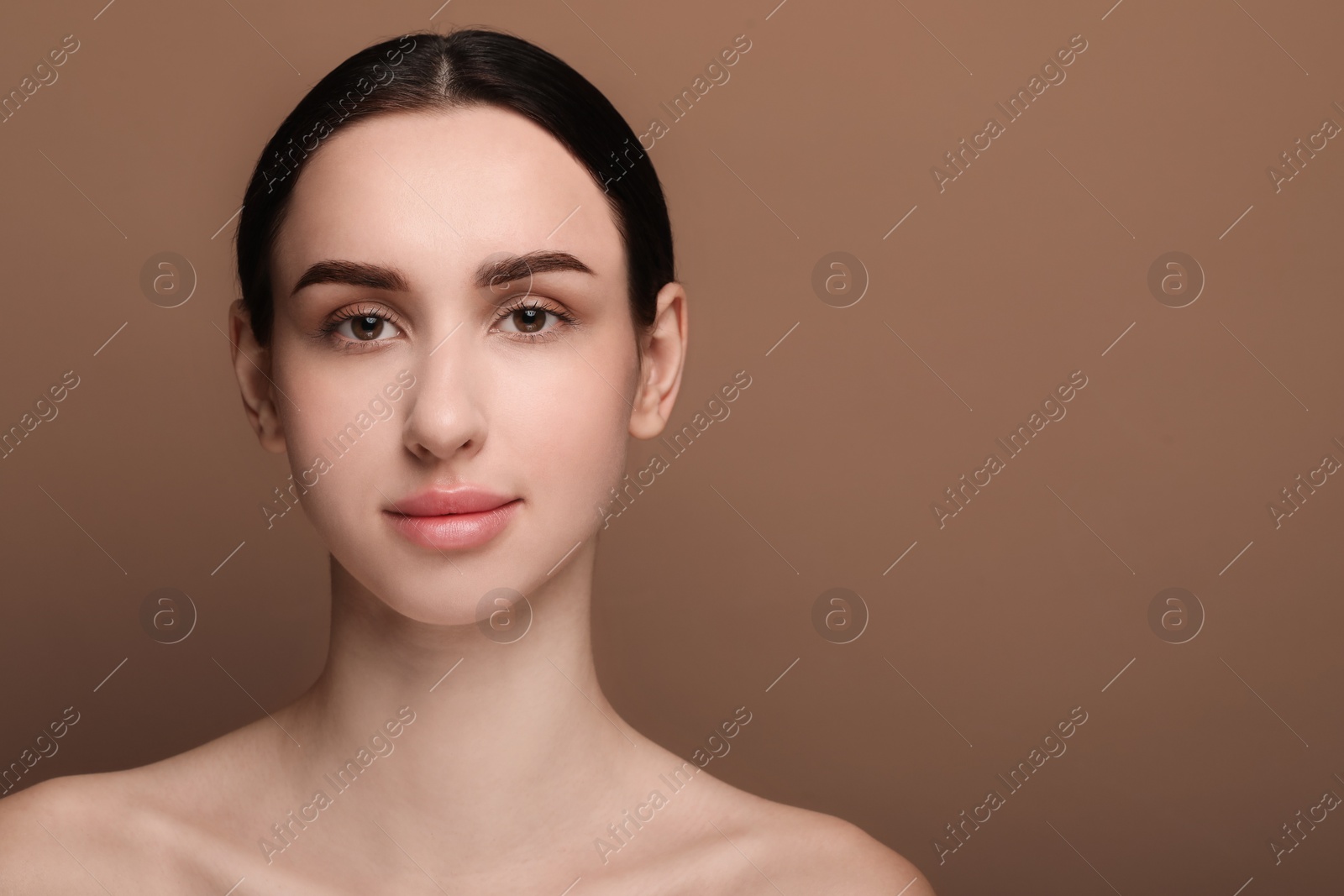 Photo of Portrait of beautiful young woman on brown background. Space for text