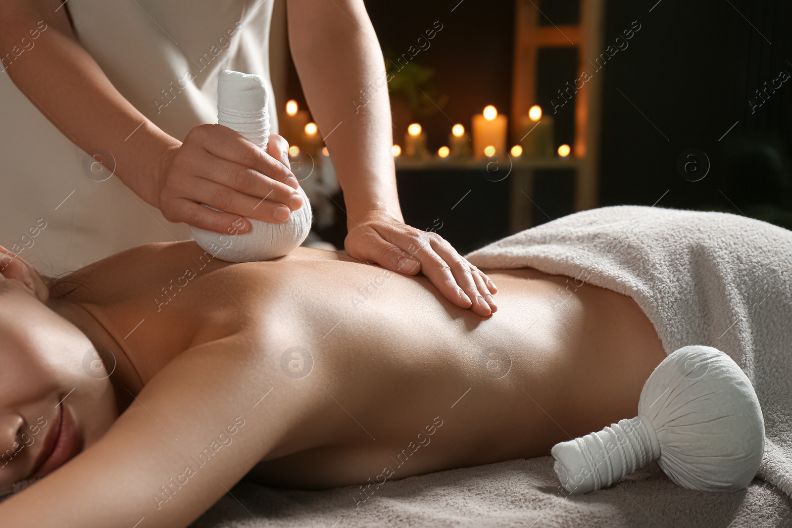 Photo of Young woman receiving herbal bag massage in spa salon, closeup