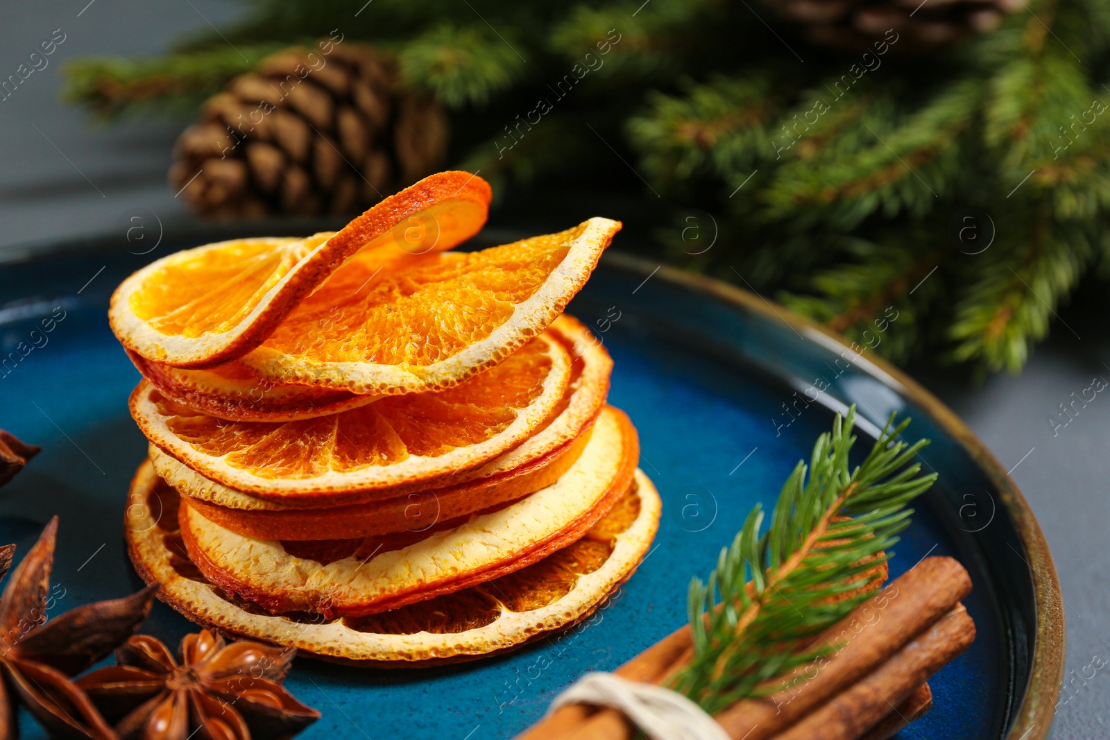 Photo of Dry orange slices, anise stars and cinnamon sticks on plate, closeup